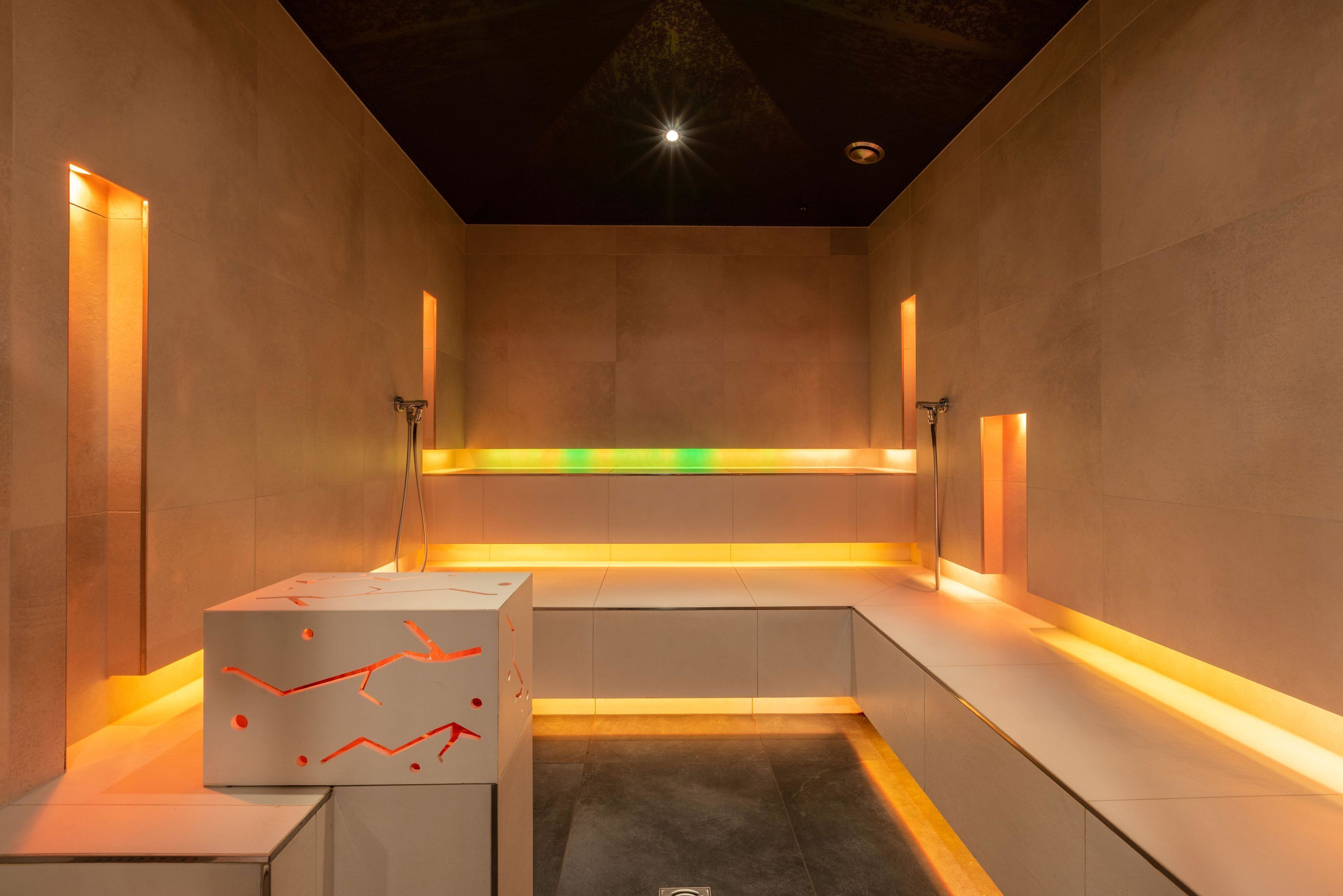 Een moderne badkamer met een centrale bank, inbouwspots en een geometrisch ontwerp op de muur.