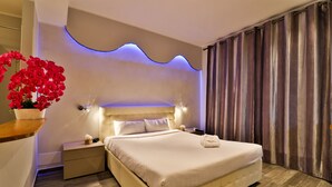 A modern hotel room with a large bed, a bedside table, a nightstand, and a wall-mounted light fixture. - Hôtel de la Mer (Vallauris)