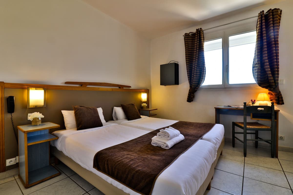 A hotel room with a large bed, bedside tables, a desk, and a chair.