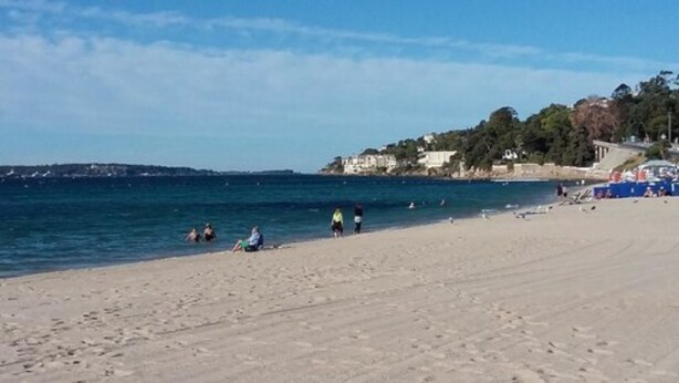 A beach with people sunbathing and swimming. There are buildings in the background. - Hôtel de la Mer (Vallauris)