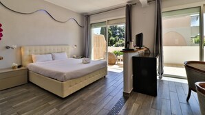 A modern bedroom with a large bed, a TV, and a balcony with outdoor furniture. - Hôtel de la Mer (Vallauris)