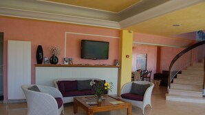 A lobby with wicker furniture, a flat-screen TV, a staircase, and a radiator. - Hôtel de la Mer (Vallauris)
