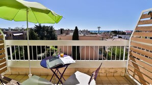 A balcony with a green umbrella, a table with a book, and two chairs. - Hôtel de la Mer (Vallauris)