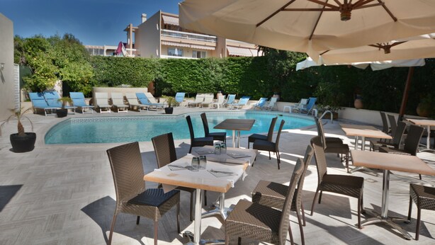 A poolside area with lounge chairs, tables, and umbrellas. - Hôtel de la Mer (Vallauris)