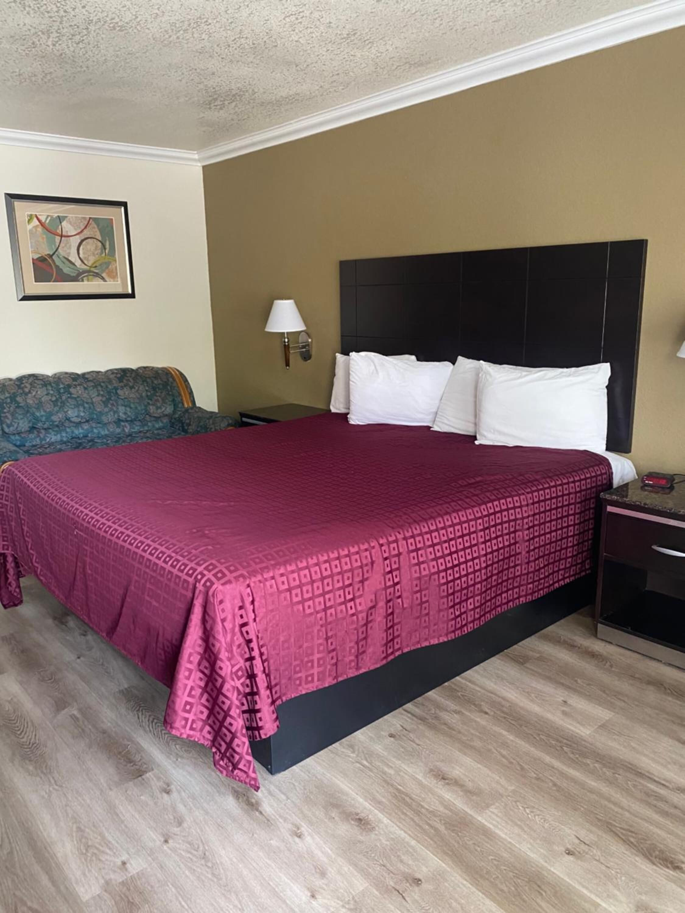Une chambre d’hôtel avec un grand lit, une table de chevet, une lampe et un canapé.
