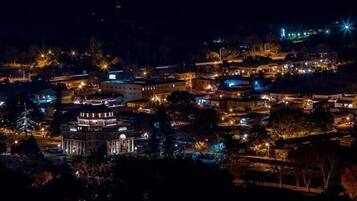 A night view of a town with illuminated buildings, including a prominent circular structure in the center.