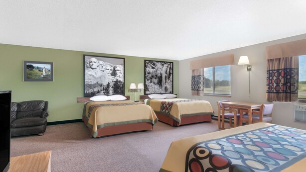 Habitación de hotel con dos camas, un sofá, un televisor y un comedor.
