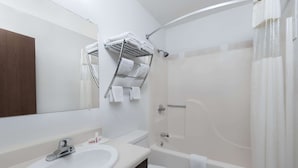 Un baño moderno con un lavamanos blanco, un inodoro y una bañera. Hay un perchero con toallas dobladas sobre el lavamanos.