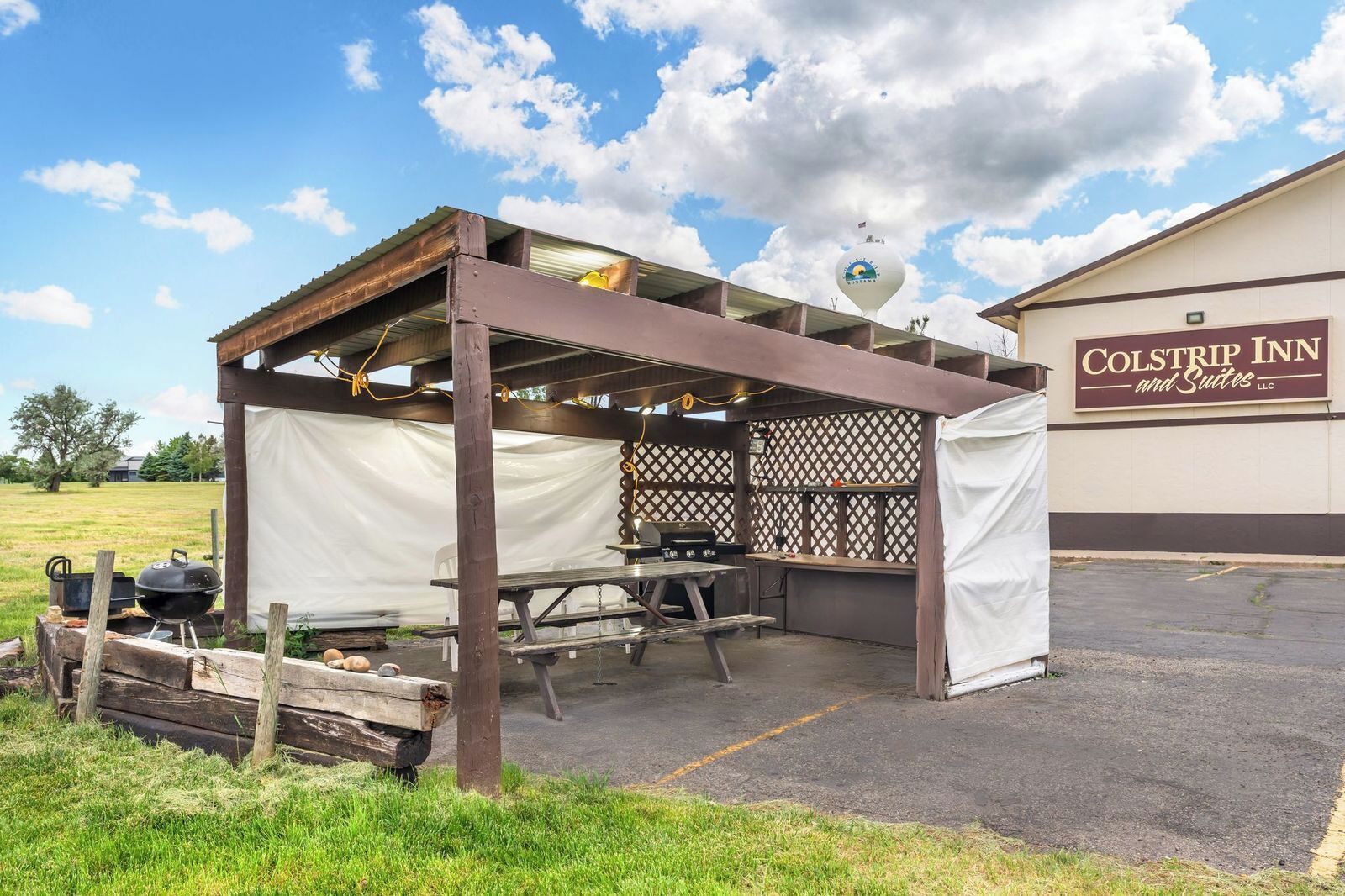 A covered outdoor seating area with a grill, tables, and a tent.