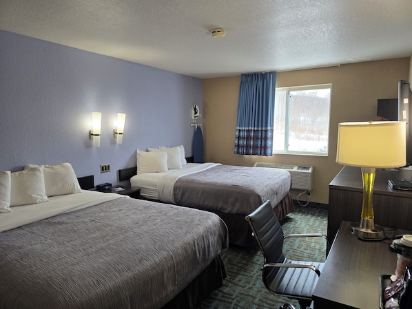 Une chambre d’hôtel avec deux lits, un bureau, une chaise, une lampe et une fenêtre avec des rideaux.