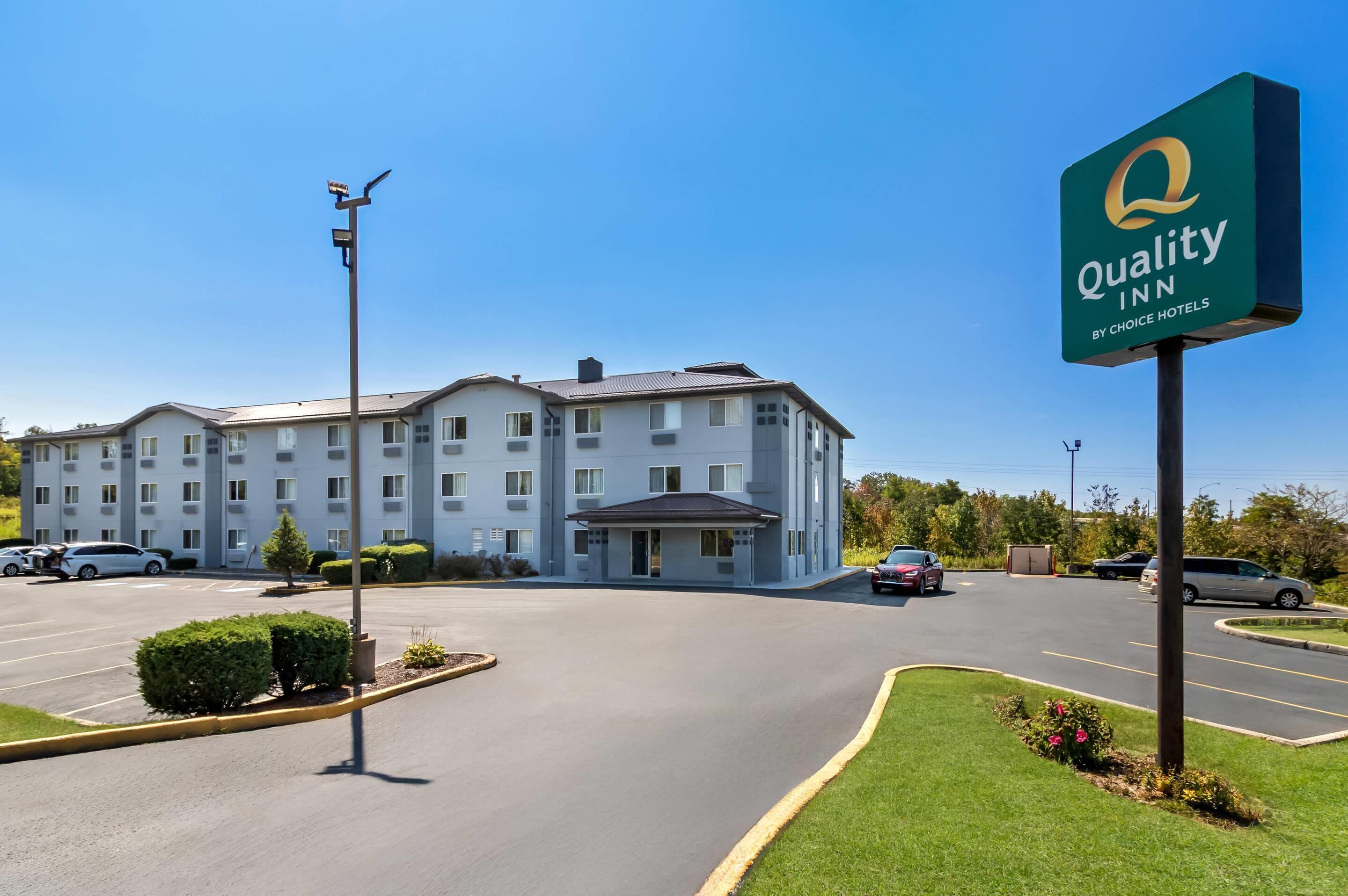 Hotel Quality Inn con estacionamiento, cielo despejado y un edificio con múltiples ventanas.
