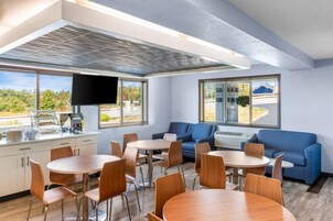 Una habitación de hotel moderna con zona de comedor, sofá y televisor.