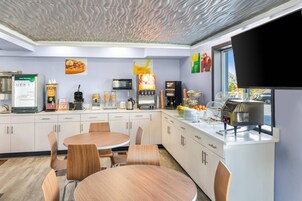 Una cocina moderna con una mesa de comedor redonda, armarios blancos y diversos electrodomésticos.