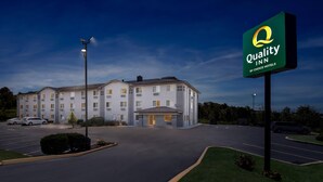 A Quality Inn by Choice Hotels building with a parking lot and a signboard.