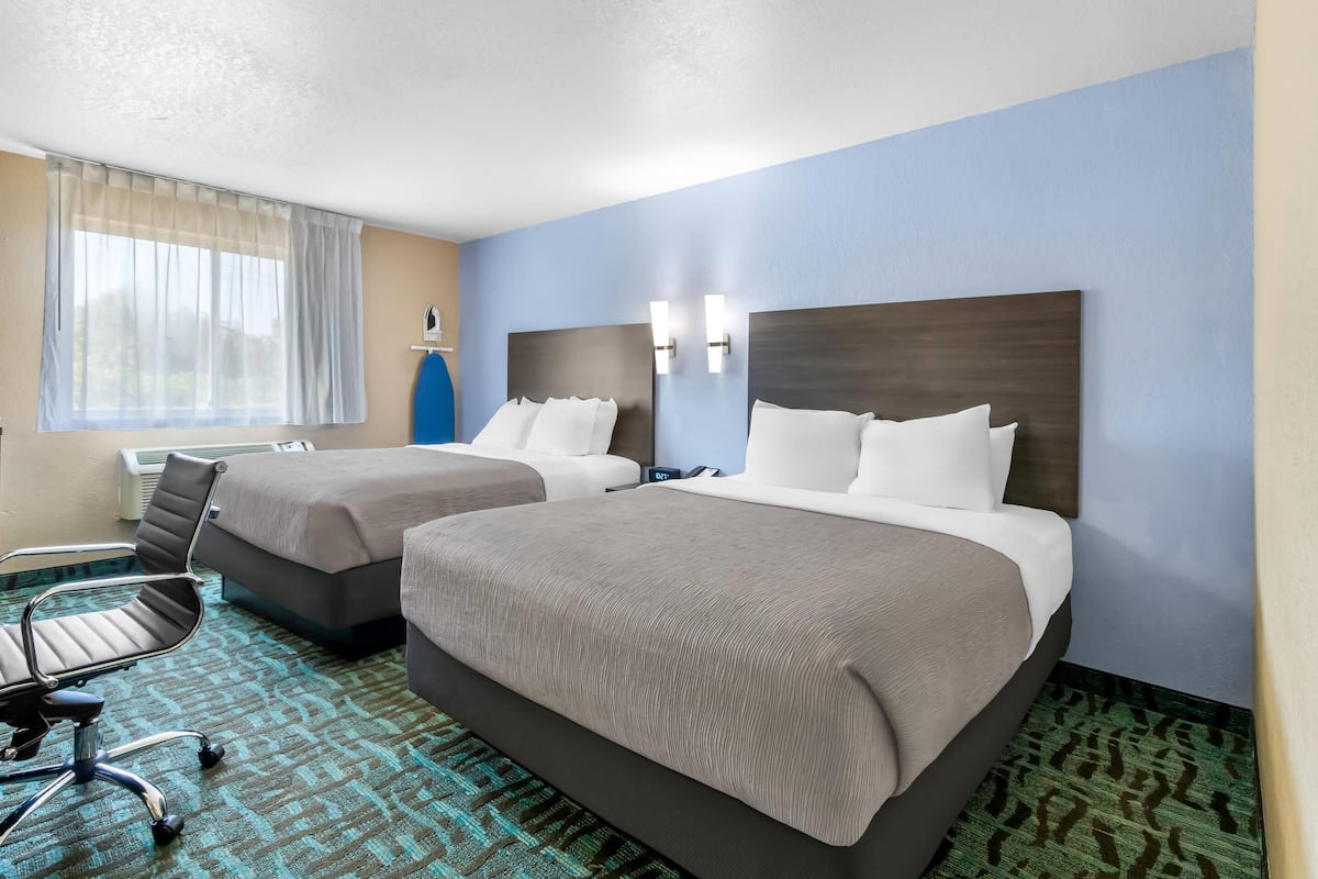 Une chambre d’hôtel avec deux lits, un bureau et une chaise.