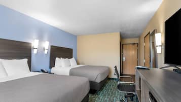 A hotel room with two beds, a desk with a computer, a chair, and a TV.