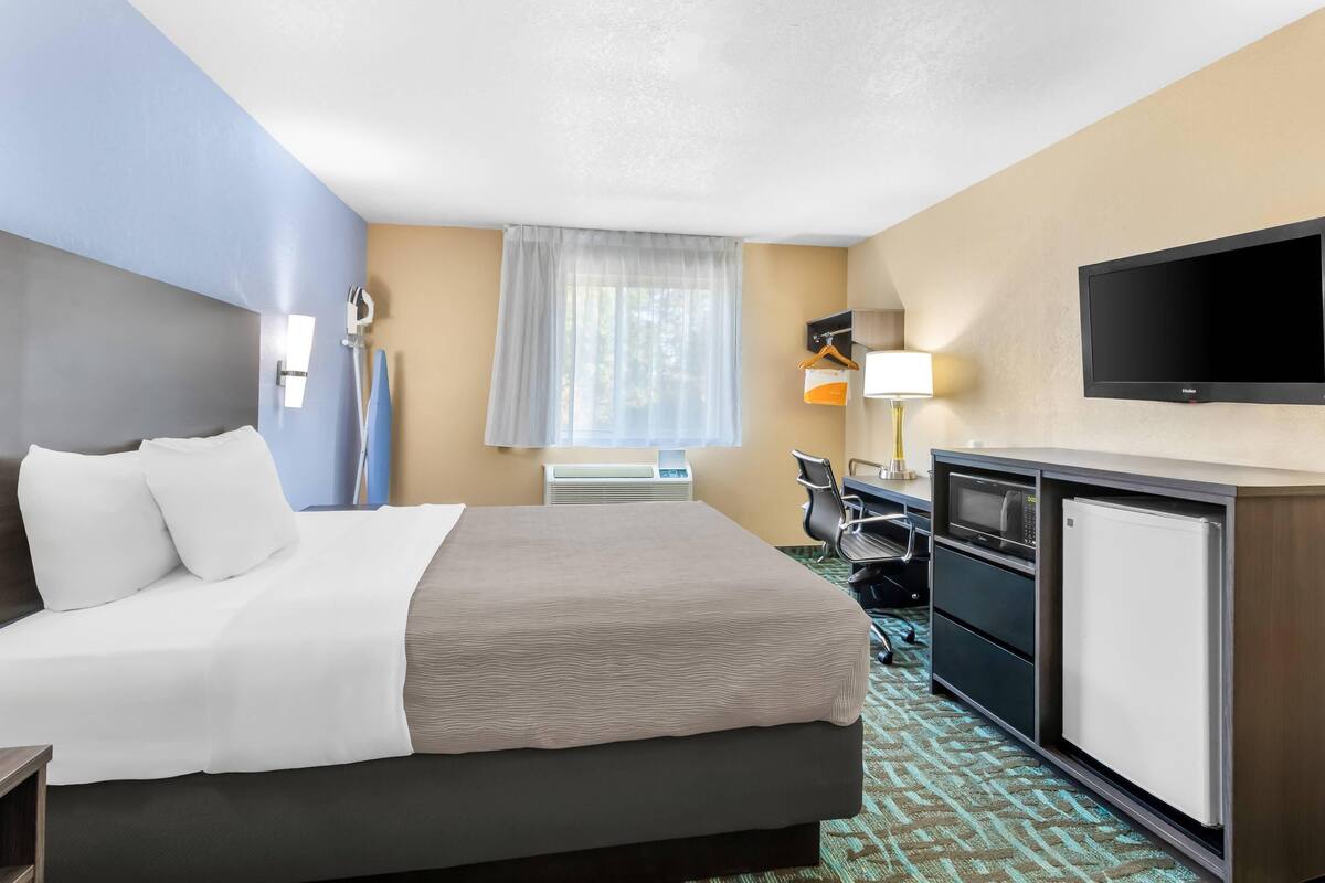 Une chambre d’hôtel équipée d’un lit, d’un bureau, d’une chaise, d’une télévision et d’un mini-bar.