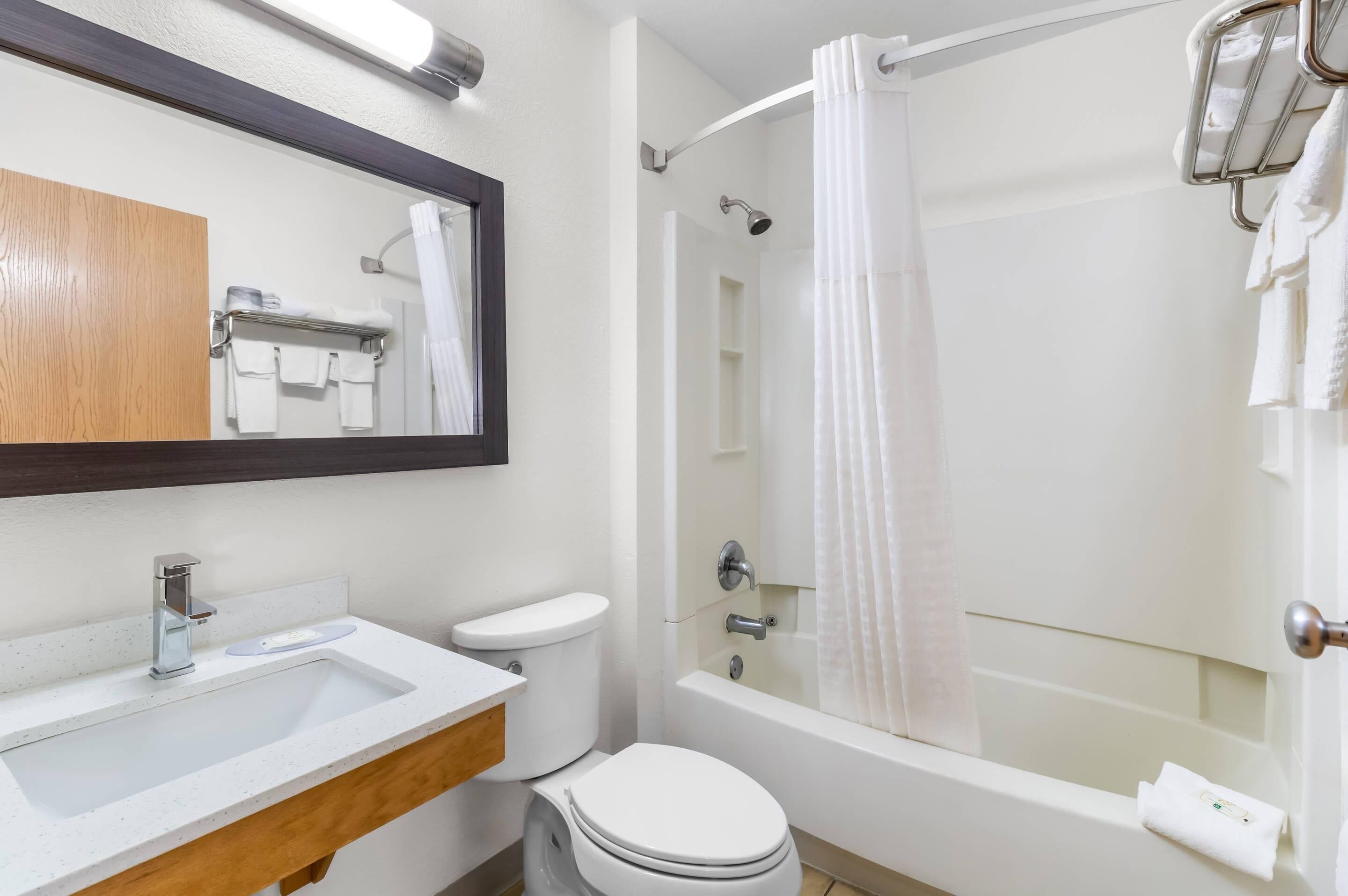 A modern bathroom with a sink, toilet, and bathtub.