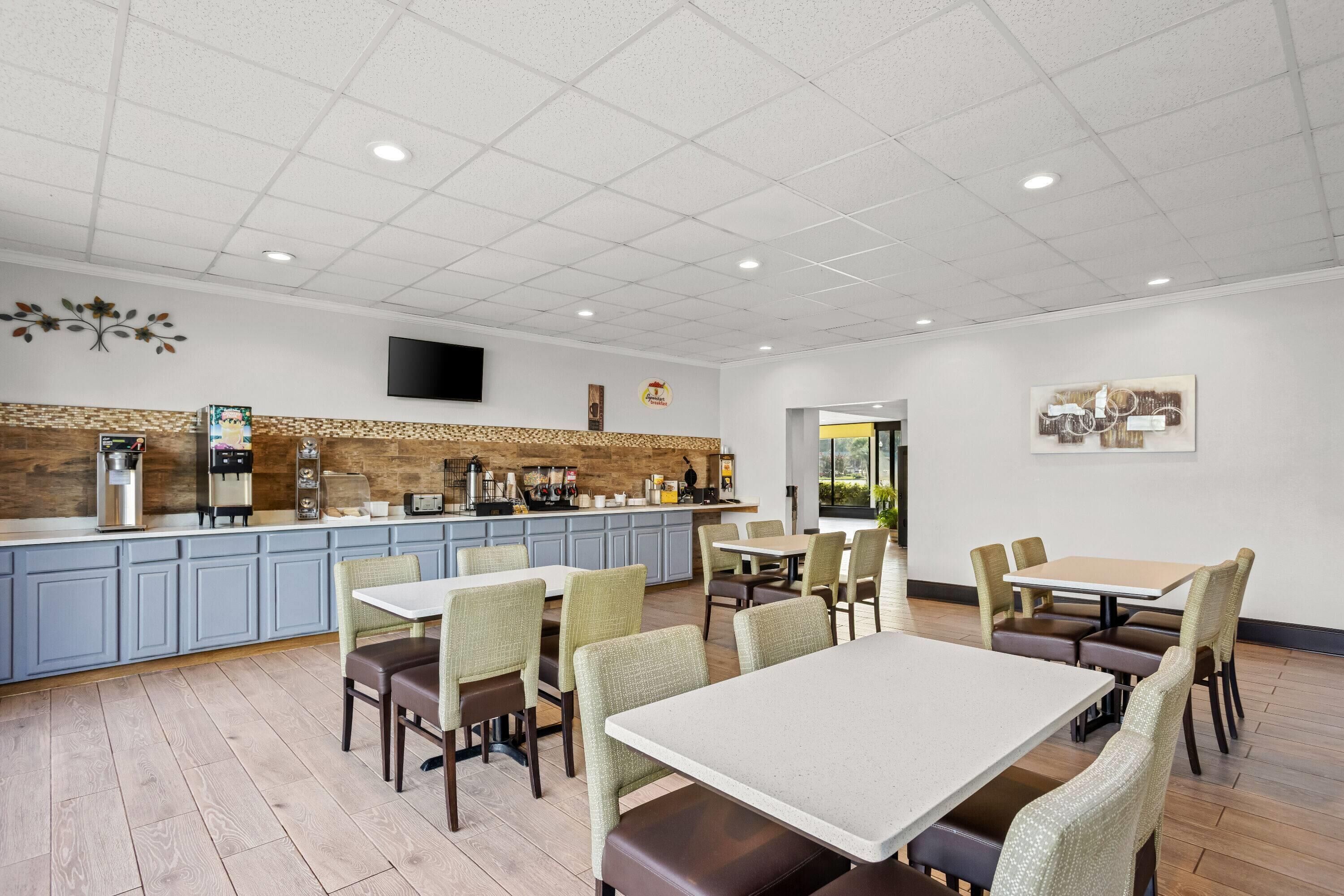 A restaurant with a counter, seating, and a television.