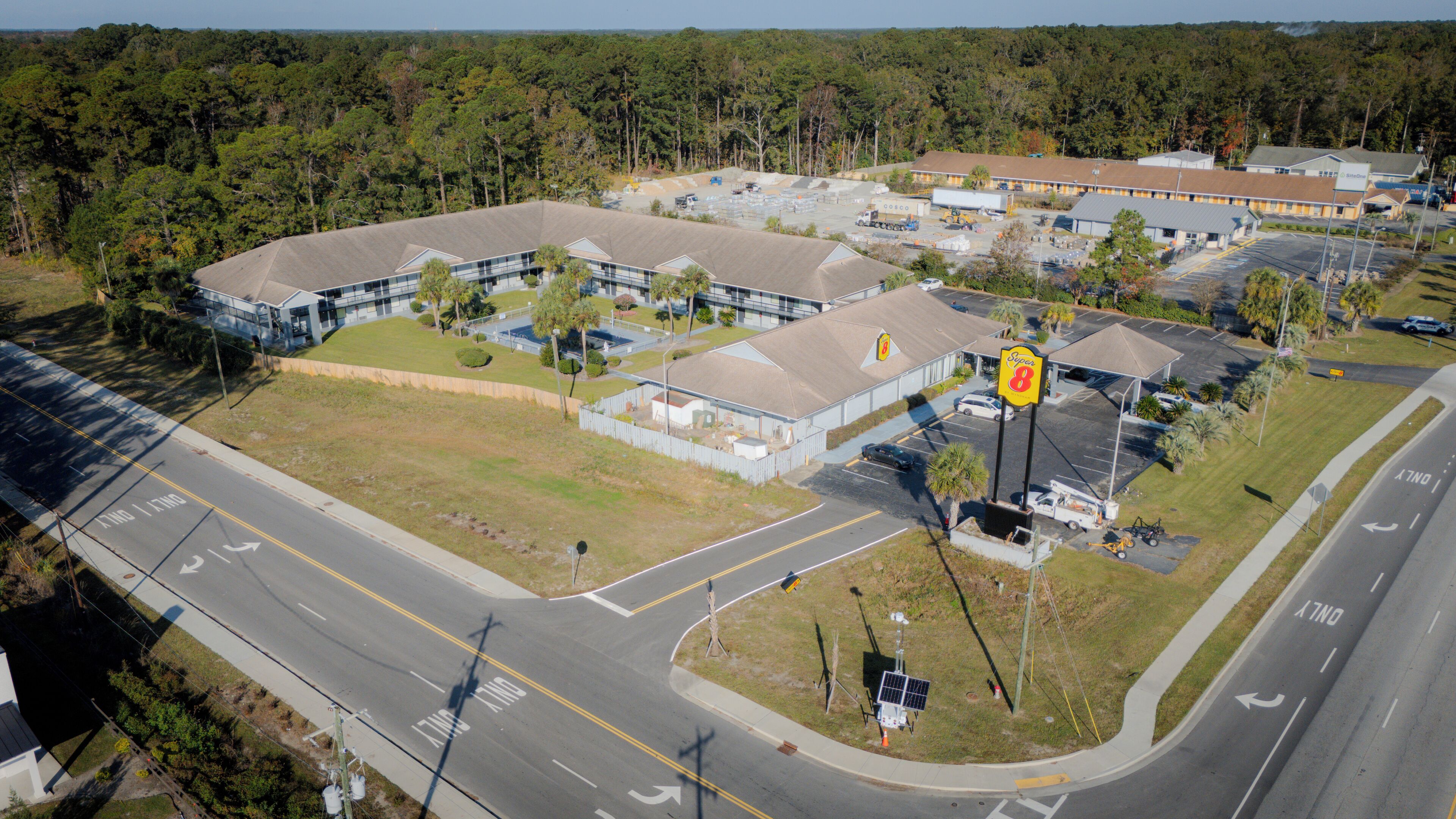 An aerial view of a commercial area with a large building, parking lots, and a Super 8 sign.