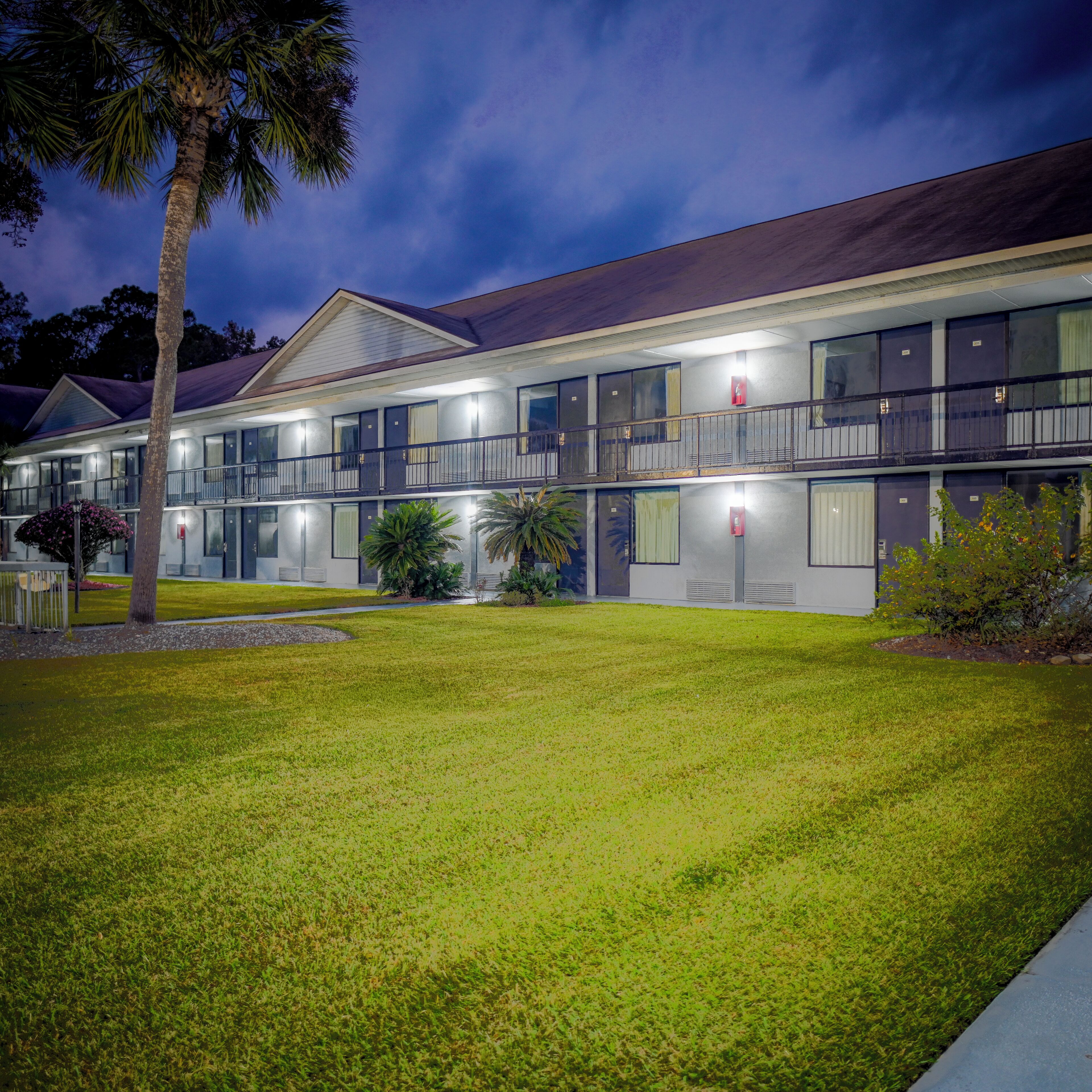 A two-story motel with a flat roof, large windows, and a well-maintained lawn.