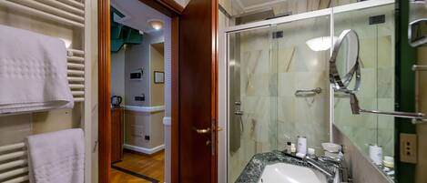 A bathroom with a glass shower enclosure, a sink with a marble countertop, and a mirror.