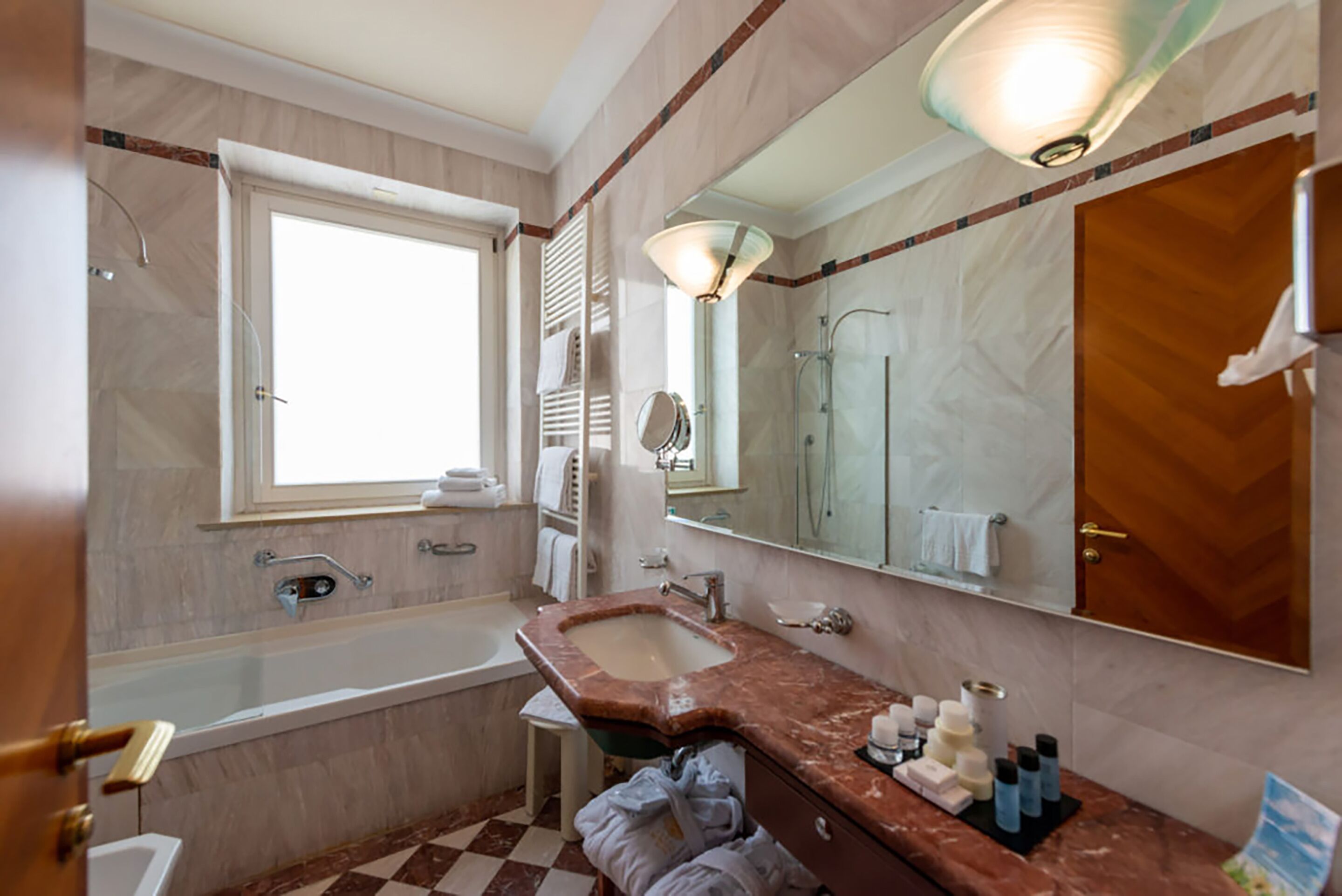 Een badkamer met een bad, wastafel en een grote spiegel.