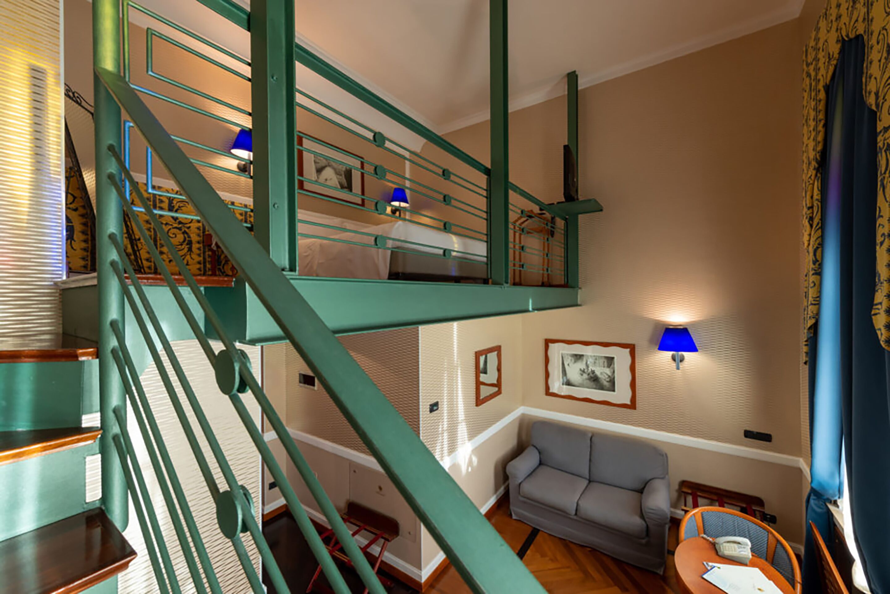 A multi-level room with a staircase, a sofa, and two wall-mounted lamps.