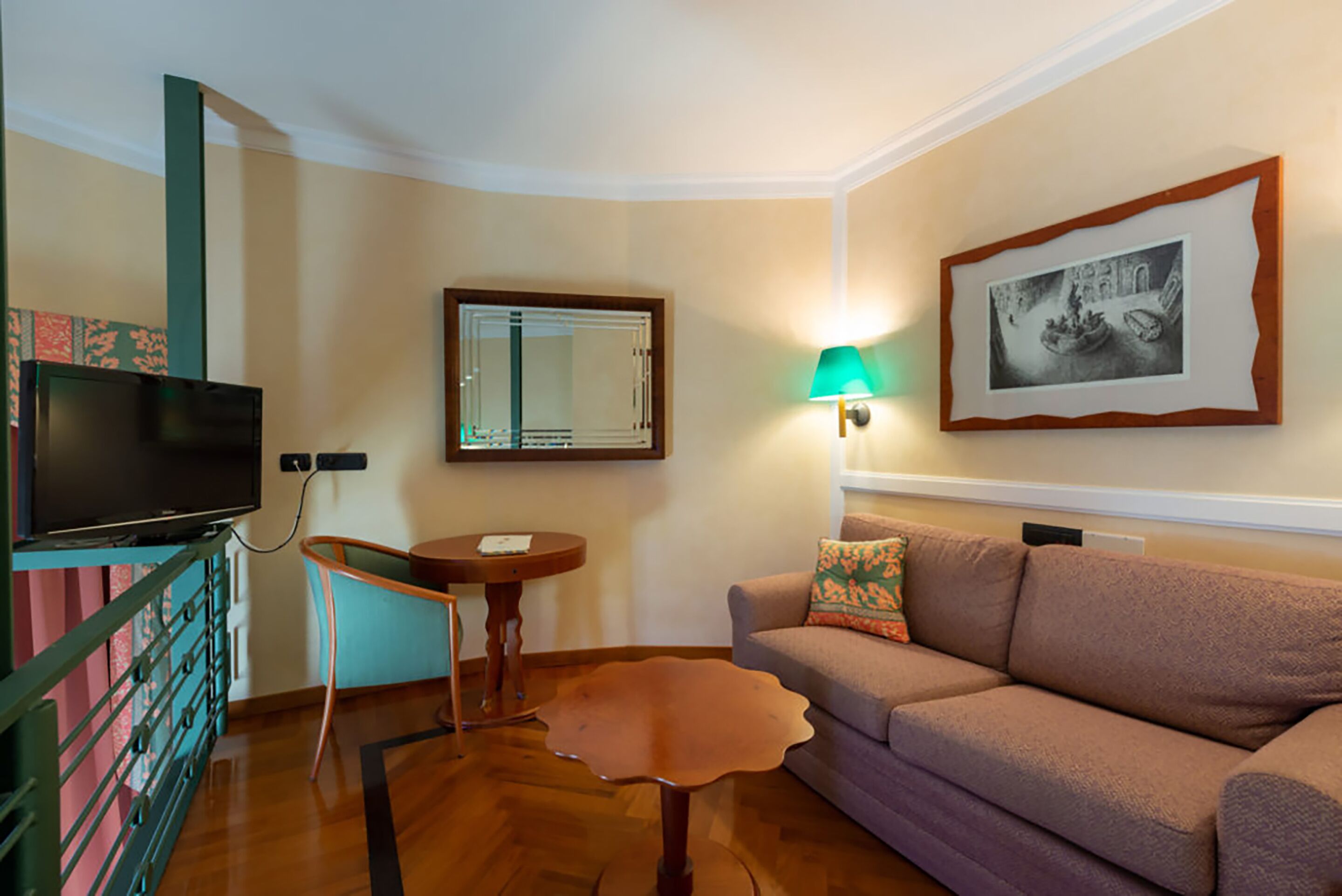 A living room with a television, a mirror, a lamp, a sofa, and a table.