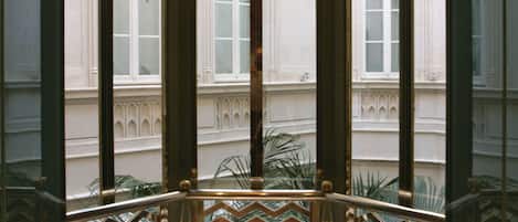A corner room with a view of a building's facade, a patterned glass door, and a metal railing.