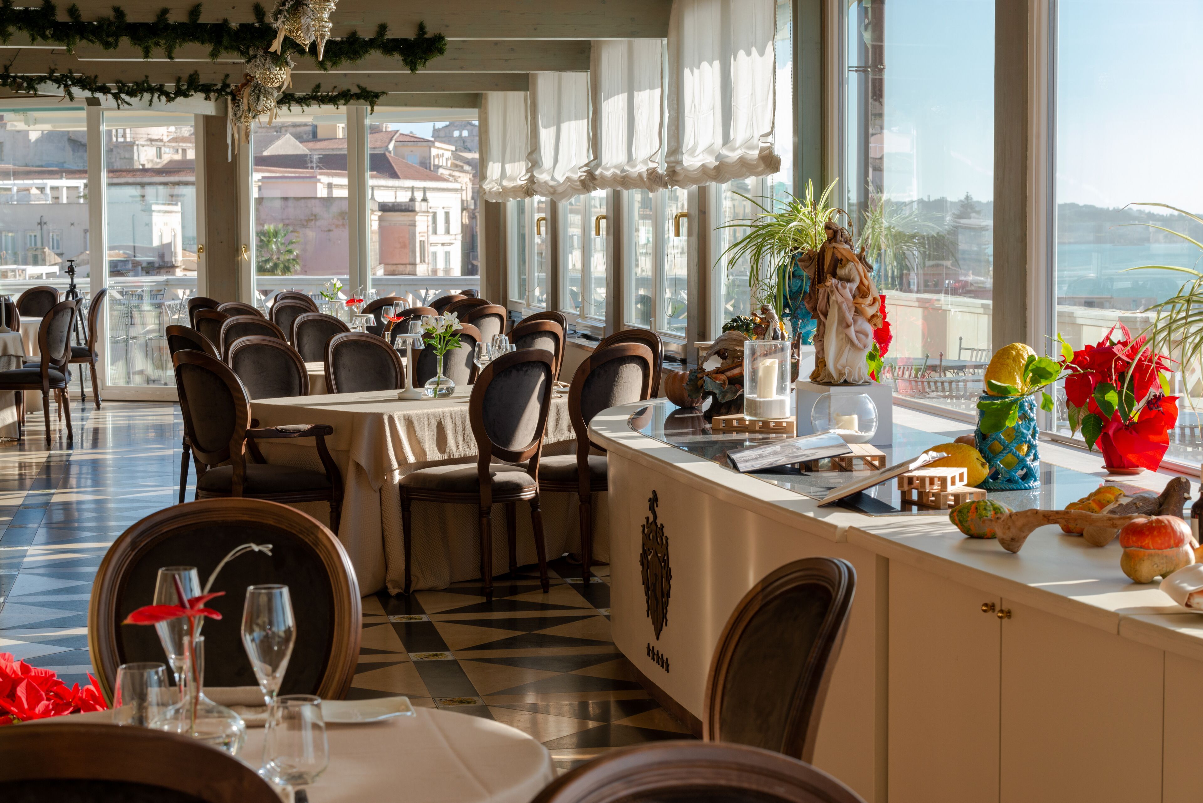 A restaurant with a checkered floor, multiple tables, chairs, and a view of buildings through large windows.