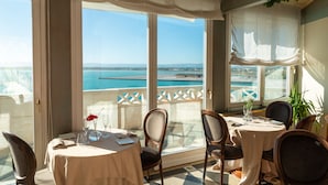 Un comedor con una mesa lista para dos personas, con vistas a la costa.
