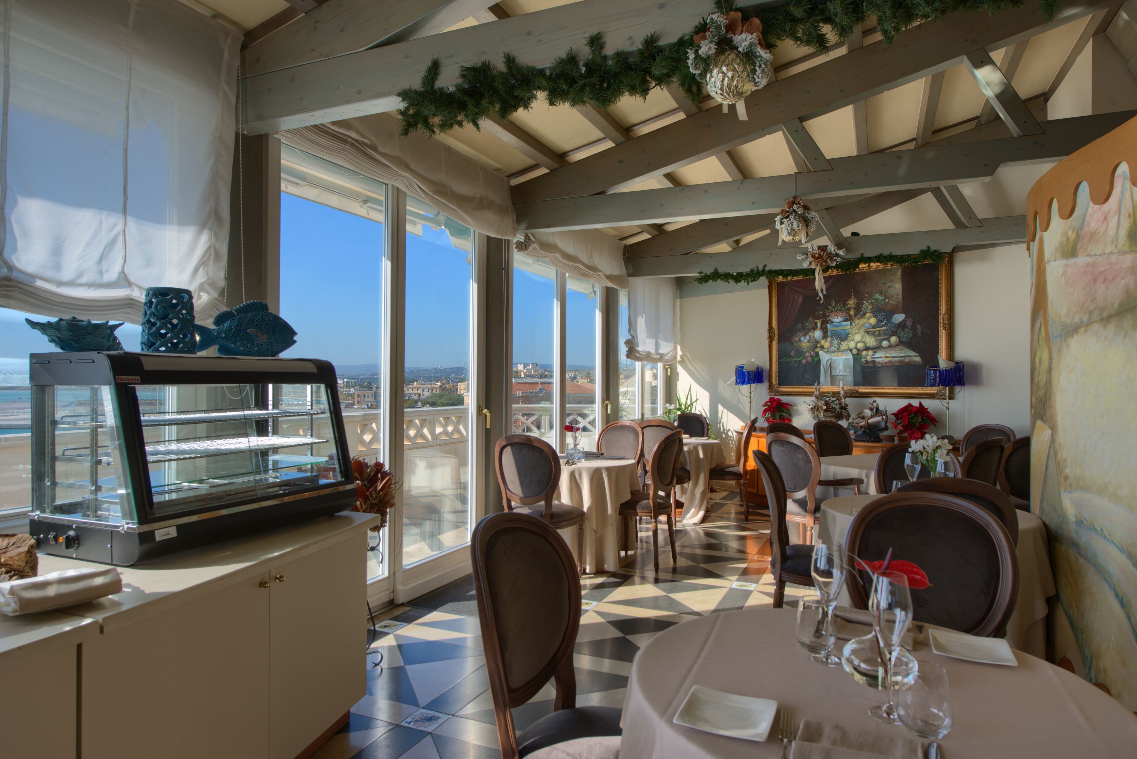 Restaurante com vista para a cidade, com balcão de buffet, mesas e cadeiras.