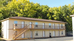 Un motel à deux étages avec un escalier central, de nombreuses portes et un parking.