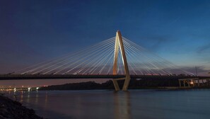 Eine Schrägseilbrücke in der Dämmerung, mit freiem Blick auf die Brückenkonstruktion und das darunterliegende Wasser.