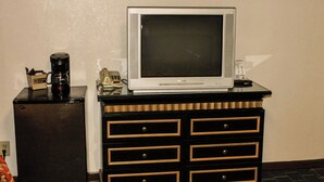 Une télévision posée sur une commode, une machine à café et un téléphone.