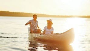 Ein Paar sitzt in einem Kanu auf dem Wasser bei Sonnenuntergang.