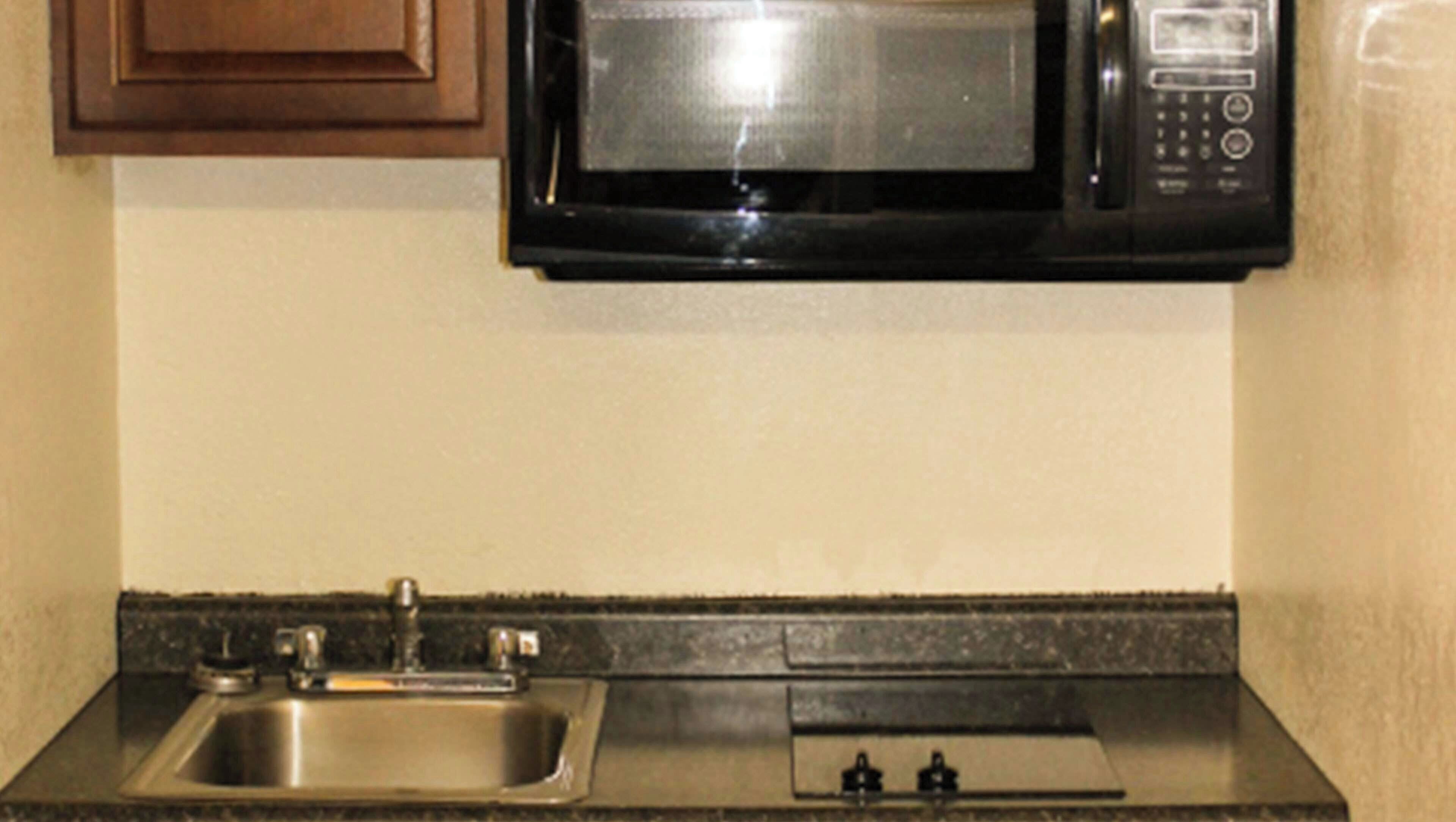 A kitchen with a stainless steel sink, a microwave, and a faucet.