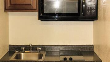 A kitchen with a stainless steel sink, a microwave, and a faucet.