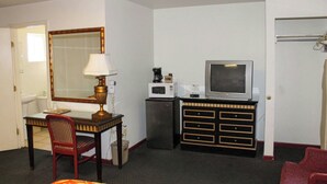Une chambre d’hôtel équipée d’un bureau, d’une chaise, d’une télévision, d’un four à micro-ondes et d’une commode.