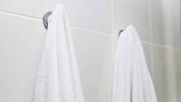 Bañera con ducha, toallas, jabón, shampoo