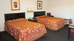 Une chambre d’hôtel avec deux lits, un bureau, une chaise et une lampe.