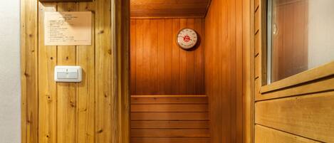 Una sauna con paredes de madera, un termómetro visible y una toalla en el banco.