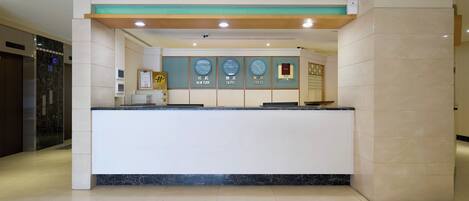 Un mostrador de recepción de diseño moderno y elegante, con encimera de mármol y un reloj que muestra diferentes zonas horarias.