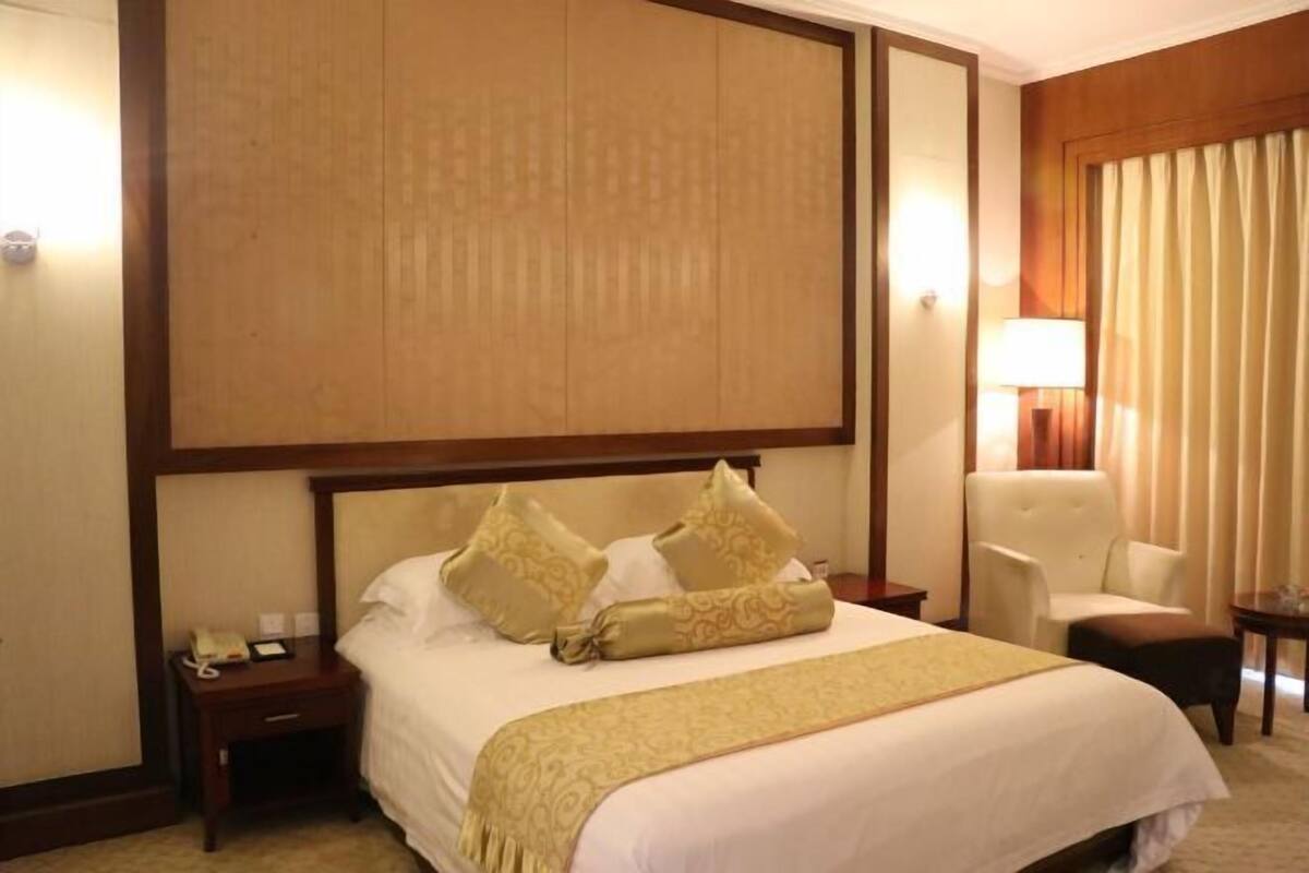 Une chambre d’hôtel avec un grand lit, deux tables de chevet, une chaise et une lampe.