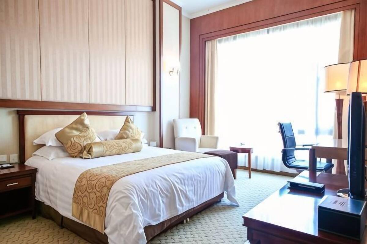 Une chambre d’hôtel avec un grand lit, un bureau avec une lampe, une chaise et un téléviseur.