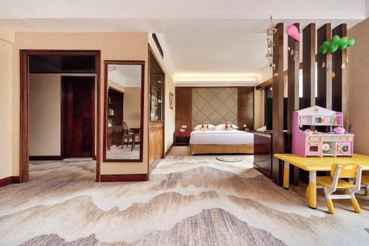 A hotel room with a bed, a desk, a chair, a mirror, and a wardrobe.