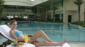 A poolside lounge area with a glass ceiling, a pool, and a view of the building's interior. - New Century Grand Hotel Xuzhou (Xuzhou)