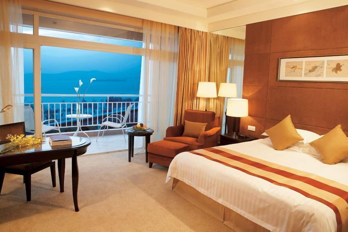 Habitación de hotel con una cama grande, un escritorio, una silla y vistas al océano.
