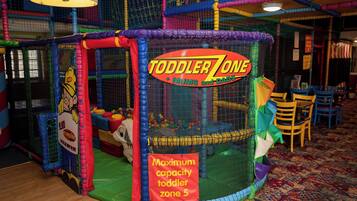 Zona de juegos para niños pequeños con un letrero que indica una capacidad máxima de 5 niños.
